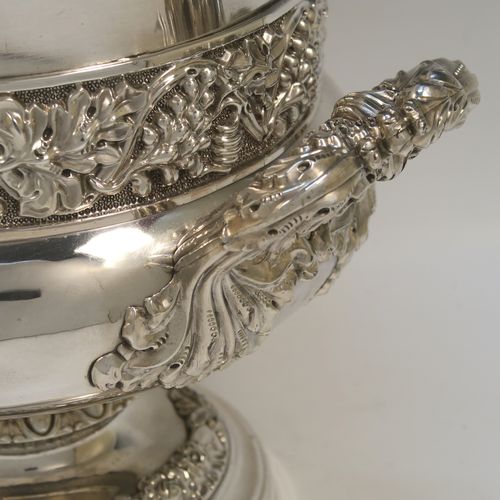 A very handsome Antique Georgian Old Sheffield plated wine cooler, in the Campagna style, with cast gadroon, scroll, and floral borders, a pair of cast side-handles, with a central applied band of grape-vine work, with its original tin-backed interior liner and cover, and all sitting on a pedestal foot. This beautiful antique Old Sheffield plated wine cooler was made in ca. 1825. The dimensions of this fine hand-made antique Old Sheffield wine cooler are height 23 cms (9 inches), and width across handles 26 cms (10.25 inches).