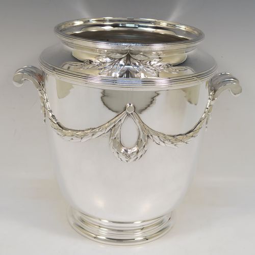 A very elegant Neoclassical style Antique Victorian silver-plated wine cooler, having a plain round body with tapering sides, with beautiful applied acanthus leaf swags, two cast scroll side-handles, and all sitting on a pedestal foot. This handsome antique silver plated wine bottle cooler was made in ca. 1880. The dimensions of this fine hand-made antique silver wine cooler are height 24 cms (9.5 inches), width across handles 25.5 cms (10 inches).   