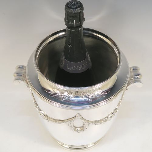 A very elegant Neoclassical style Antique Victorian silver-plated wine cooler, having a plain round body with tapering sides, with beautiful applied acanthus leaf swags, two cast scroll side-handles, and all sitting on a pedestal foot. This handsome antique silver plated wine bottle cooler was made in ca. 1880. The dimensions of this fine hand-made antique silver wine cooler are height 24 cms (9.5 inches), width across handles 25.5 cms (10 inches).