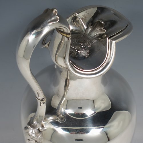 An Antique Victorian Sterling Silver wine ewer, having a plain round baluster body, an insulated scroll handle, a hinged lid with with floral finial over a shaped spout, and all sitting on a round pedestal foot. Made by the Barnard Brothers of London in 1850. The dimensions of this fine hand-made antique sterling silver wine ewer are height 32 cms (12.5 inches), length 14 cms (5.5 inches), and it weighs approx. 790g (25.5 troy ounces).