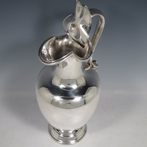 An Antique Victorian Sterling Silver wine ewer, having a plain round baluster body, an insulated scroll handle, a hinged lid with with floral finial over a shaped spout, and all sitting on a round pedestal foot. Made by the Barnard Brothers of London in 1850. The dimensions of this fine hand-made antique sterling silver wine ewer are height 32 cms (12.5 inches), length 14 cms (5.5 inches), and it weighs approx. 790g (25.5 troy ounces).