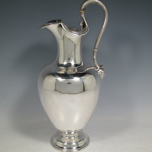 An Antique Victorian Sterling Silver wine ewer, having a plain round baluster body, an insulated scroll handle, a hinged lid with with floral finial over a shaped spout, and all sitting on a round pedestal foot. Made by the Barnard Brothers of London in 1850. The dimensions of this fine hand-made antique sterling silver wine ewer are height 32 cms (12.5 inches), length 14 cms (5.5 inches), and it weighs approx. 790g (25.5 troy ounces).