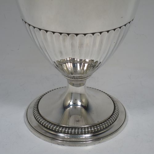 A very handsome and rare Antique Georgian Sterling Silver wine ewer, having an amphora style round bellied body, with applied gadroon borders and hand-chased half-fluted decoration, a hinged lid with cast anthemion leaf finial and a classical scroll handle, and all sitting on a pedestal foot. Made by Daniel Smith and Robert Sharp of London in 1784. The dimensions of this fine hand-made antique silver wine ewer are height 31 cms (12.25 inches), length 17 cms (6.75 inches), and it weighs approx. 840g (27 troy ounces).