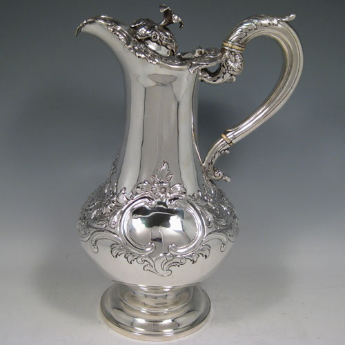 A large and very handsome Antique Scottish Sterling Silver wine ewer, William IV having a bellied body with hand-chased floral decoration, an insulated scroll handle with anthemion thumb-piece, a hinge lid with a cast feature floral finial, a spout with an applied cast floral border, and all sitting on a plain round pedestal foot. This beautiful antique silver wine ewer was made by Leon d Urquart of Edinburgh in 1837. The dimensions of this fine hand-made silver ewer are height 30 cms (12 inches), length 20 cms (8 inches), and it weighs approx. 1,116g (36 troy ounces).