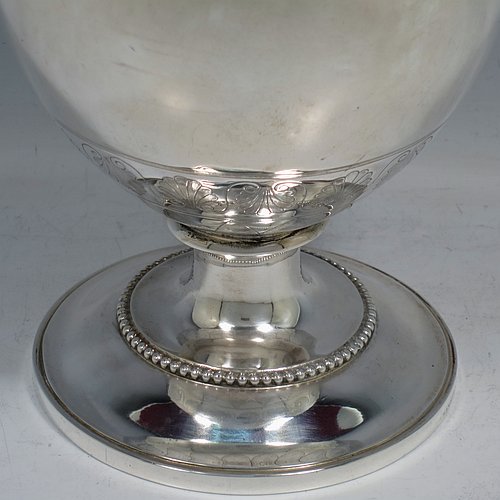 An Antique Victorian Sterling Silver wine ewer, having an amphora style round bellied body, with a band of hand-engraved floral decoration, together with applied bead borders, a lid with flat invisible hinge, a scroll handle with thumb-piece, and all sitting on a pedestal foot. Made by Arthur Sibley of London in 1869. The dimensions of this fine hand-made antique silver wine ewer are height 34 cms (13.3 inches), length 16 cms (6.25 inches), and it weighs approx. 848g (27 troy ounces).