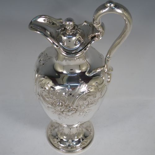 A beautiful Antique Victorian Sterling Silver wine ewer, having an amphora style round bellied body, with hand-chased floral and scroll decoration, a hinged lid with cast finial, an insulated scroll handle, and all sitting on a pedestal foot. This handsome antique silver ewer was made by the Barnard Brothers of London in 1849. The dimensions of this fine hand-made antique silver wine ewer are height 35 cms (13.5 inches), length 16.5 cms (6.5 inches), and it weighs approx. 868g (28 troy ounces).