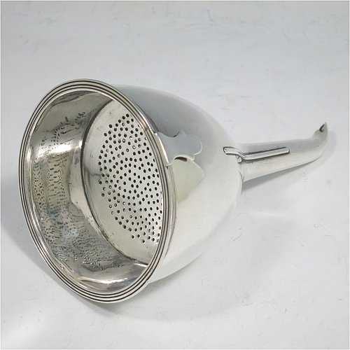 An Antique Georgian Sterling Silver wine decanting funnel, having a round body with applied reeded border and funnel struts (that allow proper aeration when decanting), a pull out strainer with a shaped clip, and an original muslin ring. Made by Alexander Field of London in 1801. Crested. The dimensions of this fine hand-made antique silver wine decanting funnel are height 14.5 cms (5.75 inches), diameter of cup 8 cms (3.25 inches), and it weighs approx. 155g (5 troy ounces).