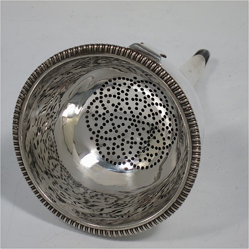 An Antique Georgian Sterling Silver wine decanting funnel, having a round body with applied reeded border and funnel struts (that allow proper aeration when decanting), a pull out hand-pierced strainer with an applied gadroon border and shaped clip, and an original muslin ring. Made by Rebecca Emes and Edward Barnard of London in 1808. The dimensions of this fine hand-made antique silver wine decanting funnel are height 15 cms (6 inches), diameter of cup 8.5 cms (3.3 inches), and it weighs approx. 162g (5.2 troy ounces).